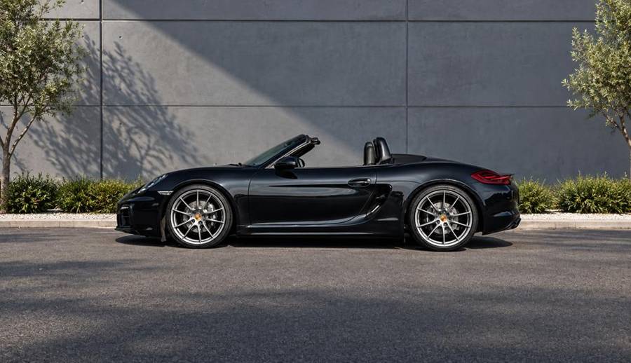 Porsche Boxster noire capote ouverte, vue de profil