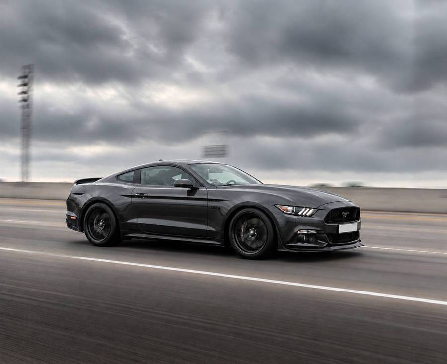 Ford Mustang GT grise en mouvement sur route, vue de profil