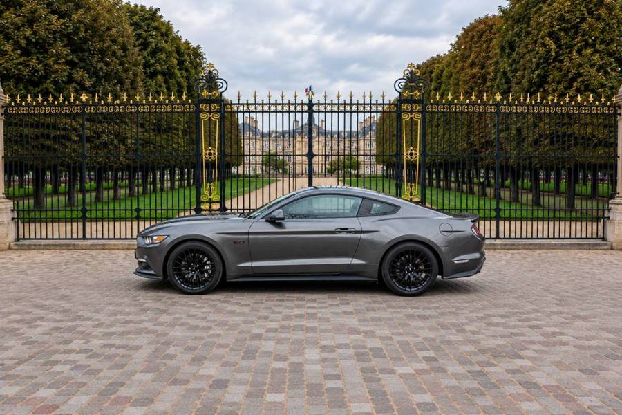 Ford Mustang GT grise, vue de profil devant une grille dorée